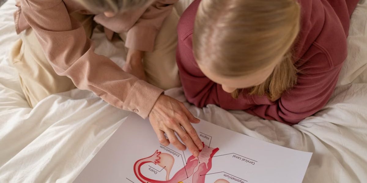 Mother and daughter studying reproductive system illustration for sex education at home.